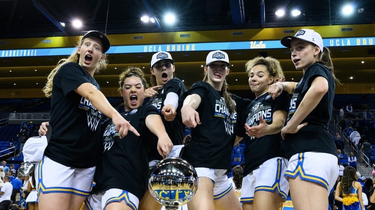 UCLA players pose with the Big Ten trophy after an...
