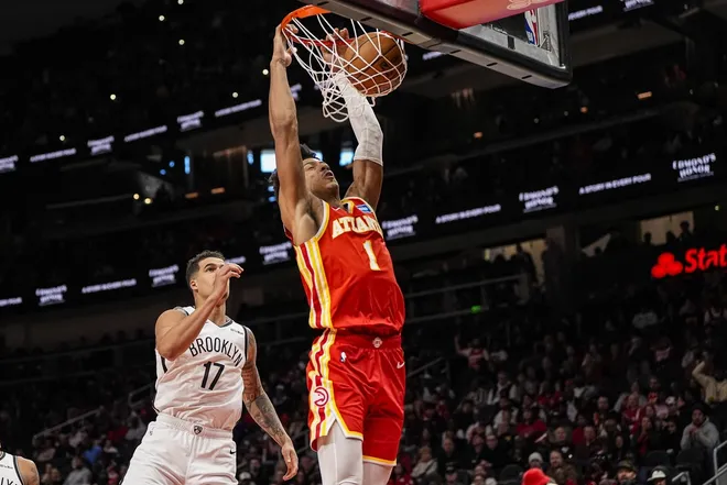 Feb 22, 2026; Atlanta, Georgia, USA; Atlanta Hawks forward Jalen Johnson (1) dunks behind Brooklyn Nets forward Michael Porter Jr. (17) during the second half at State Farm Arena.