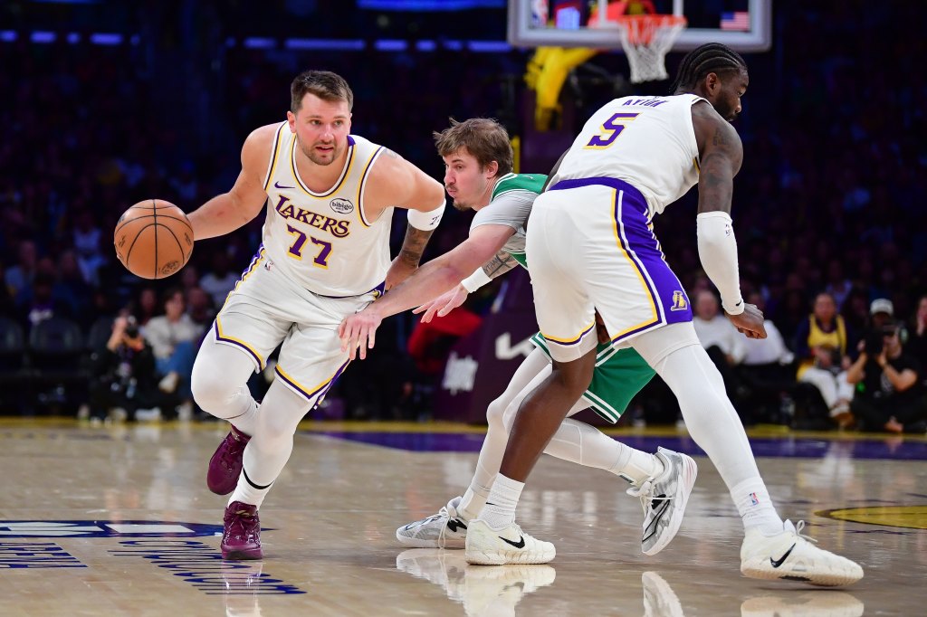 Lakers guard Luka Doncic with the basketball while being defended by Celtics guard Baylor Scheierman and Lakers center Deandre Ayton.