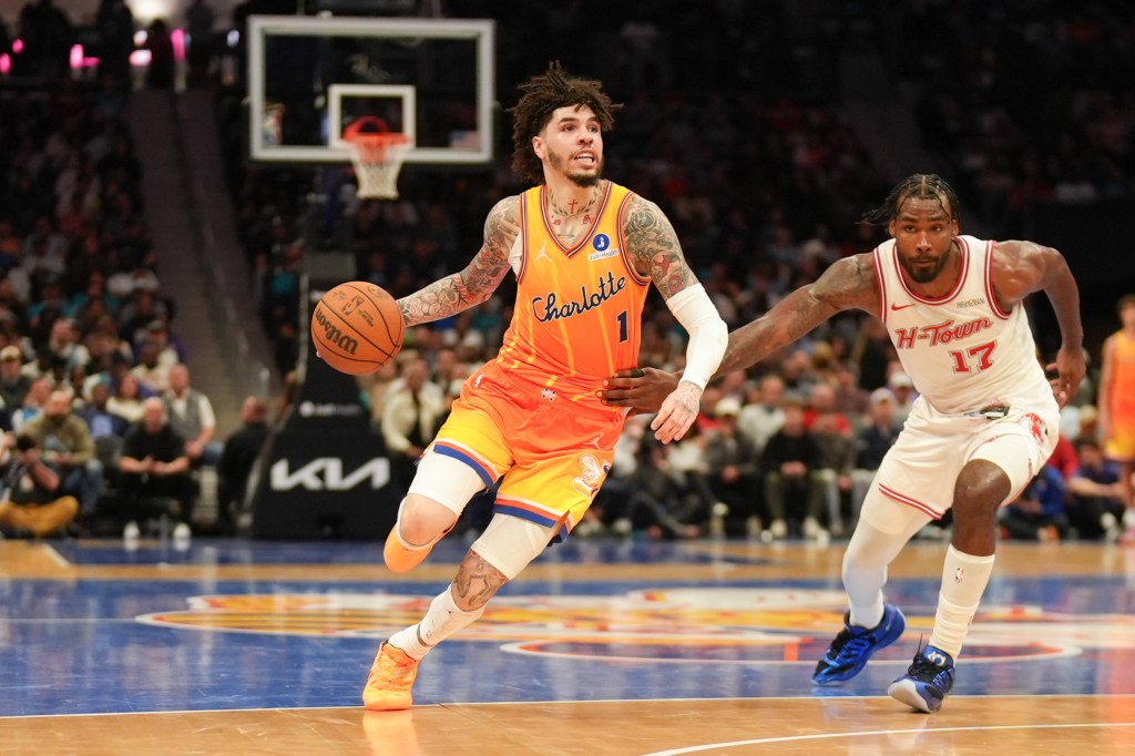 Charlotte Hornets player LaMelo Ball dribbles the ball down the court while being guarded by a Houston Rockets player.