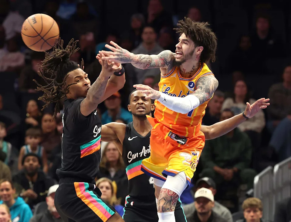 Charlotte Hornets guard LaMelo Ball passes to a teammate as he is double-teamed by San Antonio Spurs guards Stephon Castle, left, and De’Aaron Fox during action at Spectrum Center on Saturday. The Hornets defeated the Spurs 111-106.