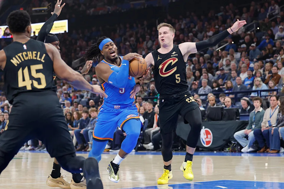 Feb 22, 2026; Oklahoma City, Oklahoma, USA; Oklahoma City Thunder guard Luguentz Dort (5) drives to the basket beside Cleveland Cavaliers guard Sam Merrill (5) during the first half at Paycom Center. Mandatory Credit: Alonzo Adams-Imagn Images
