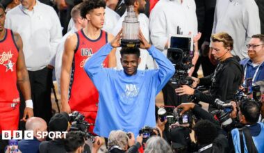 Anthony Edwards holds the All-Star MVP trophy above his head as photographers take his picture