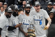 Dallas Mavericks guard Kyrie Irving holds the championship trophy and guard Luka Doncic...
