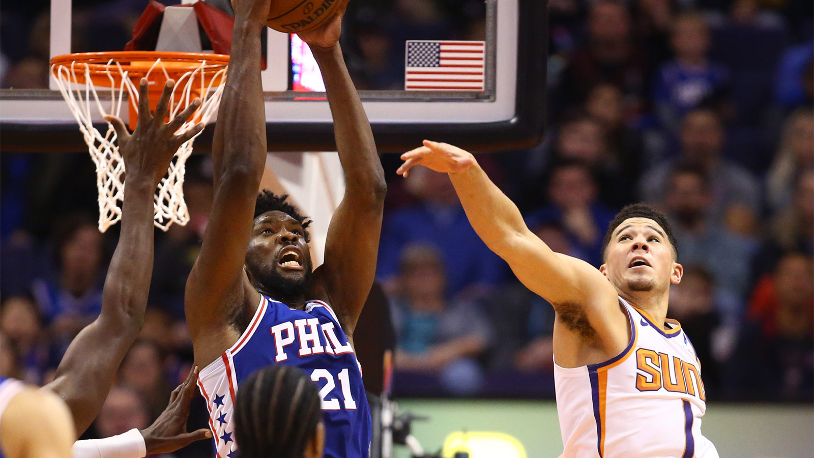 76ers center Joel Embiid (21) grabs a pass against Phoenix Suns guard Devin Booker (1) in the second half at Talking Stick Resort Arena