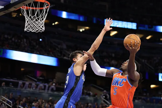 Dec 19, 2024; Orlando, Florida, USA; Oklahoma City Thunder guard Luguentz Dort (5) drives to the hoop guarded by Orlando Magic forward Tristan da Silva (23) in the fourth quarter at Kia Center. Mandatory Credit: Nathan Ray Seebeck-Imagn Images