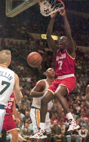 OAKLAND, : Houston Rockets Carl Herrera (R) makes a slam dunk as Golden State Warriors Clifford Rozier (background) and Chris Mullin look on 06 April in Oakland, California. The Rockets defeated the Warriors, 110-102. AFP PHOTO (Photo credit should read JOHN G. MABANGLO/AFP via Getty Images)