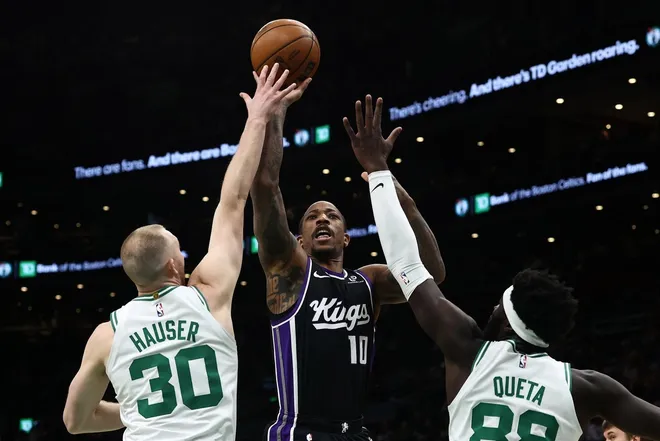 Jan 30, 2026; Boston, Massachusetts, USA; Sacramento Kings guard DeMar DeRozan (10) shoots over Boston Celtics forward Sam Hauser (30) and center Neemias Queta (88) during the first quarter at TD Garden.
