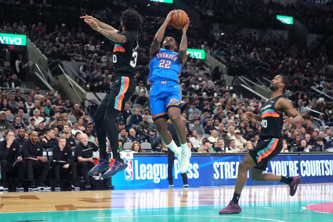 Feb 4, 2026; San Antonio, Texas, USA; Oklahoma City Thunder guard Cason Wallace (22) drives to the basket between forwards Julian Champagnie (30) and Harrison Barnes (40) during the second half at Frost Bank Center. Mandatory Credit: Scott Wachter-Imagn Images