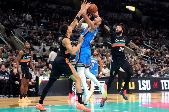 Feb 4, 2026; San Antonio, Texas, USA; Oklahoma City Thunder forward Jaylin Williams (6) drives to the basket against San Antonio Spurs forwards Carter Bryant (11) and Julian Champagnie (30) during the second half at Frost Bank Center. Mandatory Credit: Scott Wachter-Imagn Images