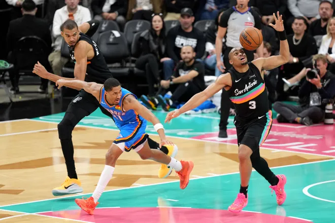 Feb 4, 2026; San Antonio, Texas, USA; San Antonio Spurs forward Keldon Johnson (3) attempts to control the ball ahead of teammate forward Victor Wembanyama (1) and Oklahoma City Thunder guard Aaron Wiggins (21) during the second half at Frost Bank Center. Mandatory Credit: Scott Wachter-Imagn Images