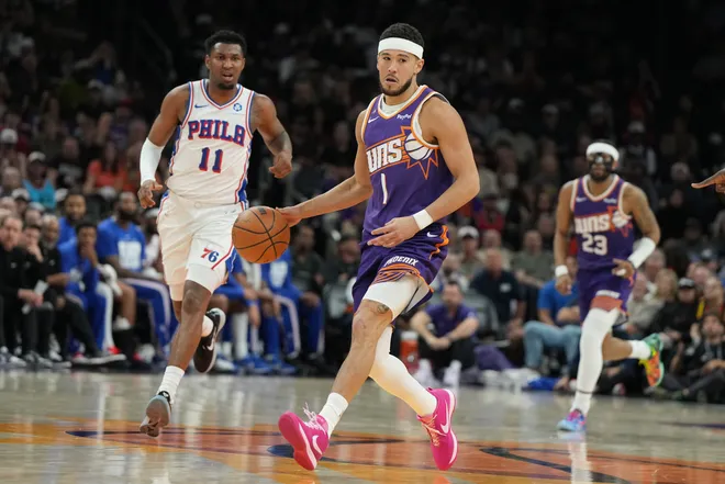 Feb 7, 2026; Phoenix, Arizona, USA; Phoenix Suns guard Devin Booker (1) drives past Philadelphia 76ers forward Justin Edwards (11) during the first half of an NBA game at Mortgage Matchup Center. Mandatory Credit: Rick Scuteri-Imagn Images