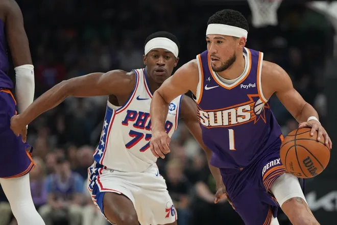 Feb 7, 2026; Phoenix, Arizona, USA; Phoenix Suns guard Devin Booker (1) drives around Philadelphia 76ers guard Vj Edgecombe (77) during the first half of an NBA game at Mortgage Matchup Center.
