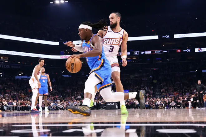 PHOENIX, ARIZONA - FEBRUARY 11: Luguentz Dort #5 of the Oklahoma City Thunder dribbles the ball against Dillon Brooks #3 of the Phoenix Suns during the first half at Mortgage Matchup Center on February 11, 2026 in Phoenix, Arizona. NOTE TO USER: User expressly acknowledges and agrees that, by downloading and or using this photograph, User is consenting to the terms and conditions of the Getty Images License Agreement. (Photo by Chris Coduto/Getty Images)