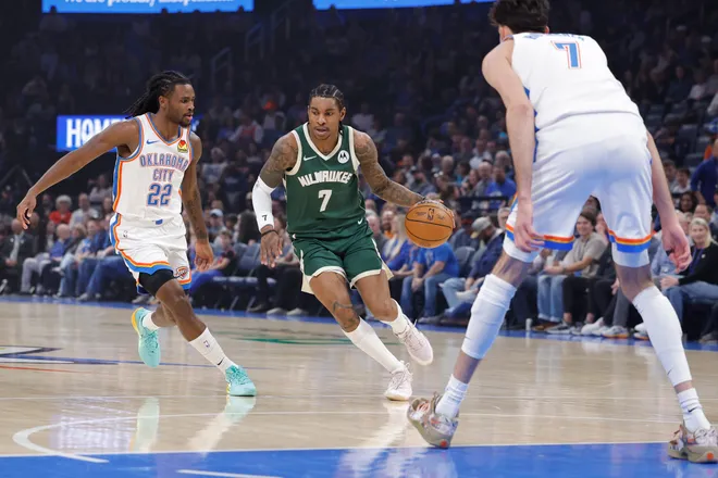 Feb 12, 2026; Oklahoma City, Oklahoma, USA; Milwaukee Bucks guard/forward Kevin Porter Jr. (7) drives between Oklahoma City Thunder guard Cason Wallace (22) and center/forward Chet Holmgren (7) during the first quarter at Paycom Center. Mandatory Credit: Alonzo Adams-Imagn Images