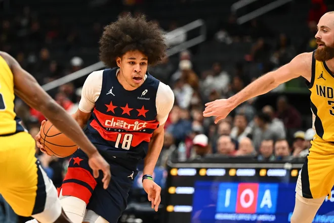 Feb 19, 2026; Washington, District of Columbia, USA; Washington Wizards forward Kyshawn George (18) dribbles as Indiana Pacers center Jay Huff (32) looks on during the first half at Capital One Arena.