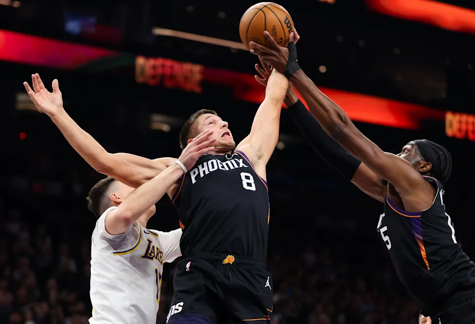 Grayson Allen #8 of the Phoenix Suns and Mark Williams #15 rebound the ball during the first half of a game against the Los Angeles Lakers at Mortgage Matchup Center on Dec. 14, 2025, in Phoenix.