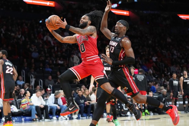Bulls guard Coby White (0) drives to the basket as Miami Heat center Bam Adebayo (13) defends during the second half of a game, Sunday, Feb. 1, 2026, in Miami. (AP Photo/Lynne Sladky)
