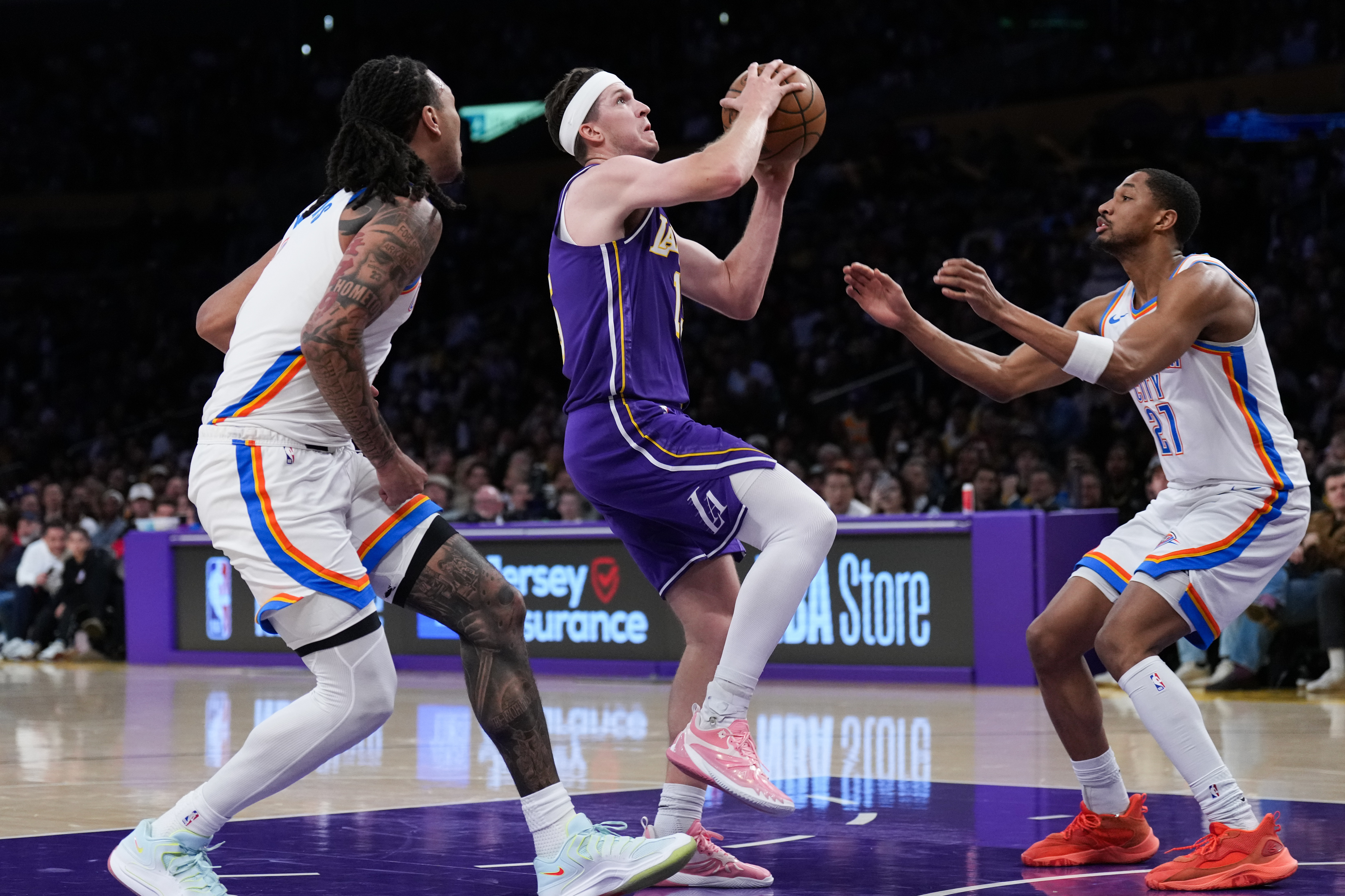 Lakers guard Austin Reaves, center, drives to the basket as...