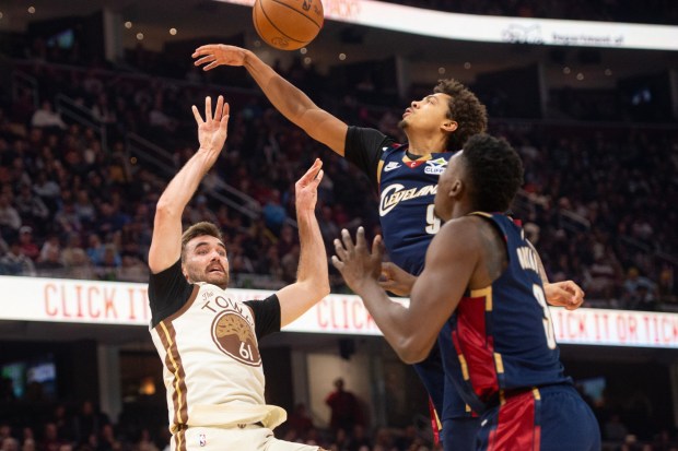 Golden State Warriors' Pat Spencer (61) shoots as Cleveland Cavaliers' Craig Porter Jr., rear, and Thomas Bryant defend during the first half of an NBA basketball game in Cleveland, Saturday, Dec. 6, 2025. (AP Photo/Phil Long)