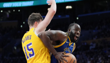 A basketball player in a blue Golden State Warriors jersey drives past a defender in a yellow Lakers jersey numbered 15 during a game.