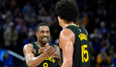 Two Golden State Warriors players, one wearing number 8 and smiling, are celebrating together on the basketball court during a game.