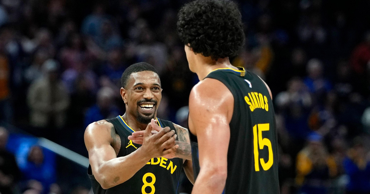 Two Golden State Warriors players, one wearing number 8 and smiling, are celebrating together on the basketball court during a game.
