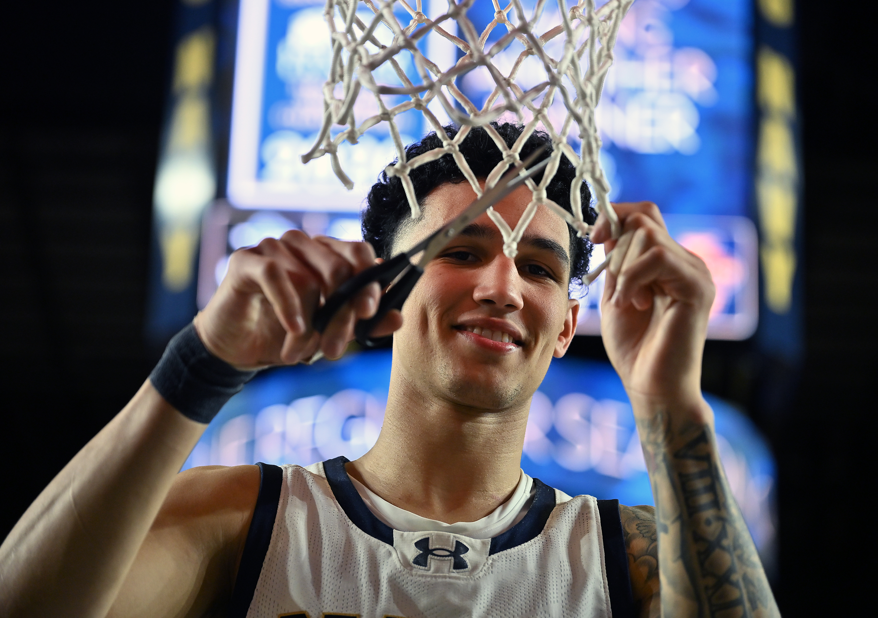 Navy Midshipmen forward Donovan Draper #11 is all smiles as he cuts a piece of the net down after the win. The Navy Midshipmen defeated the Lehigh Mountain Hawks, 72-49, to become the Patriot League Regular Season Champions in men's NCAA basketball. (Paul W. Gillespie/Staff)