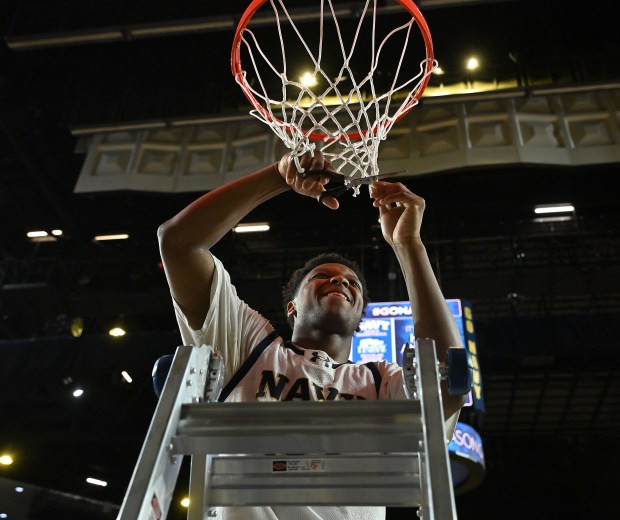 /Navy Midshipmen guard Jordan Pennick #21 cuts a piece of the net down after the win. The Navy Midshipmen defeated the Lehigh Mountain Hawks, 72-49, to become the Patriot League Regular Season Champions in men's NCAA basketball. (Paul W. Gillespie/Staff)