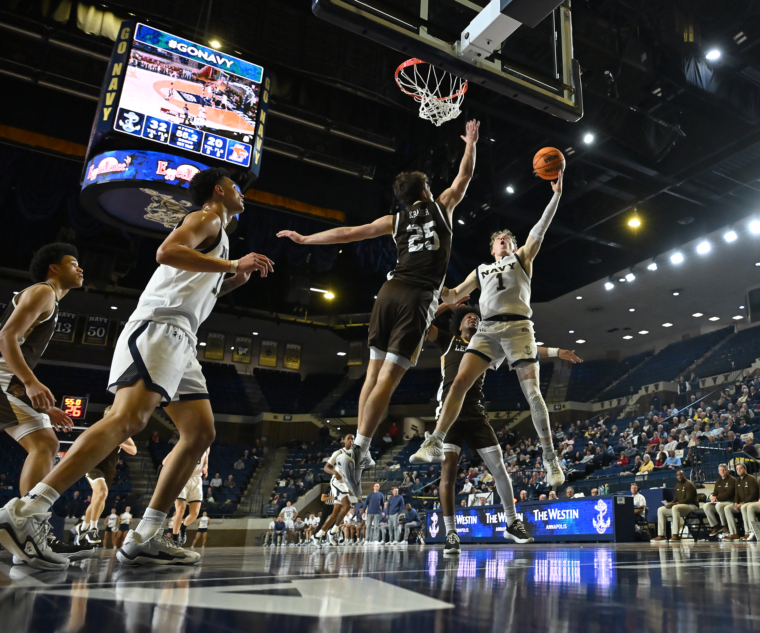 Navy Midshipmen guard Austin Benigni #1 goes sky high on a shot attempt over Lehigh Mountain Hawks guard Peter Kramer #25 during the first half. The Navy Midshipmen host the Lehigh Mountain Hawks in men's NCAA basketball. (Paul W. Gillespie/Staff)