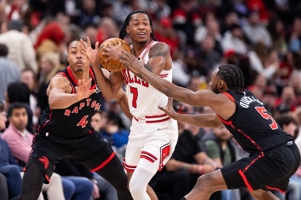 Chicago Bulls guard Rob Dillingham (7) is defended by Toronto Raptors forward Scottie Barnes (4) and guard Immanuel Quickley (5) in the first half of a game against the Toronto Raptors at the United Center in Chicago on Feb. 19, 2026. (Josh Boland/Chicago Tribune)