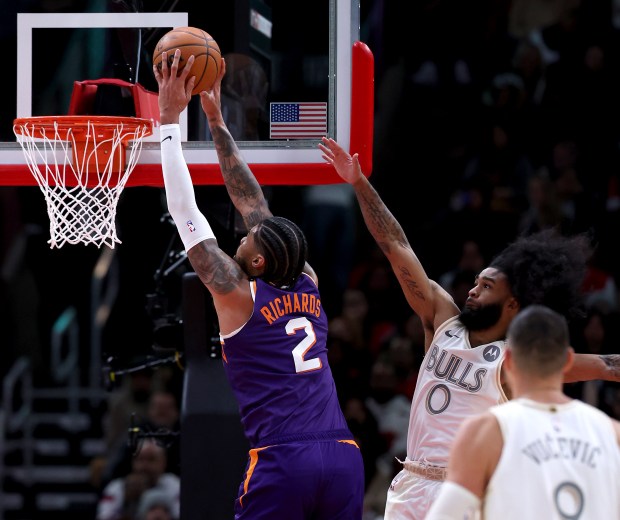 Suns center Nick Richards (2) dunks beside Bulls guard Coby White on Feb. 22, 2025, at the United Center. (Chris Sweda/Chicago Tribune)