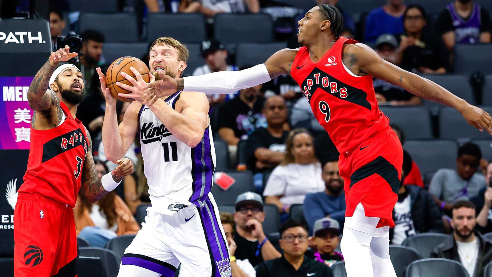 Sacramento Kings forward/center Domantas Sabonis (11) fights for a rebound against Toronto Raptors forward Brandon Ingram (3) and forward/guard RJ Barrett (9) during the third quarter at Golden 1 Center.