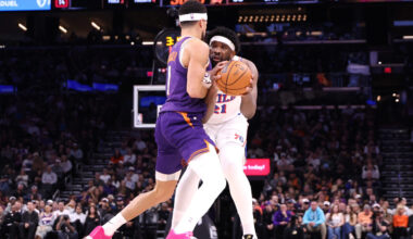 Devin Booker #1 of the Phoenix Suns fouls Joel Embiid #21 of the Philadelphia 76ers during the firs...