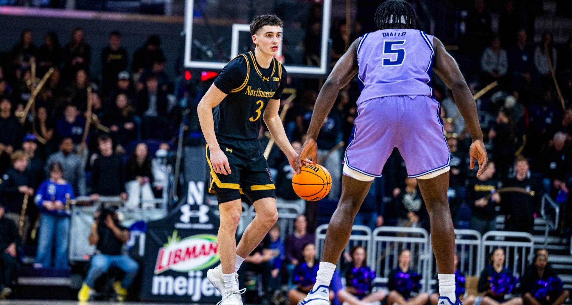 A player in black dribbles the ball up the court.