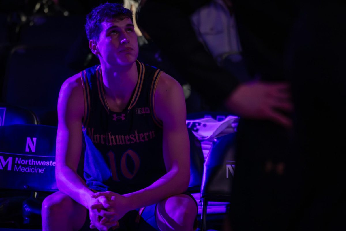 A Northwestern player’s face is illuminated by blue light while sitting down during introductions.