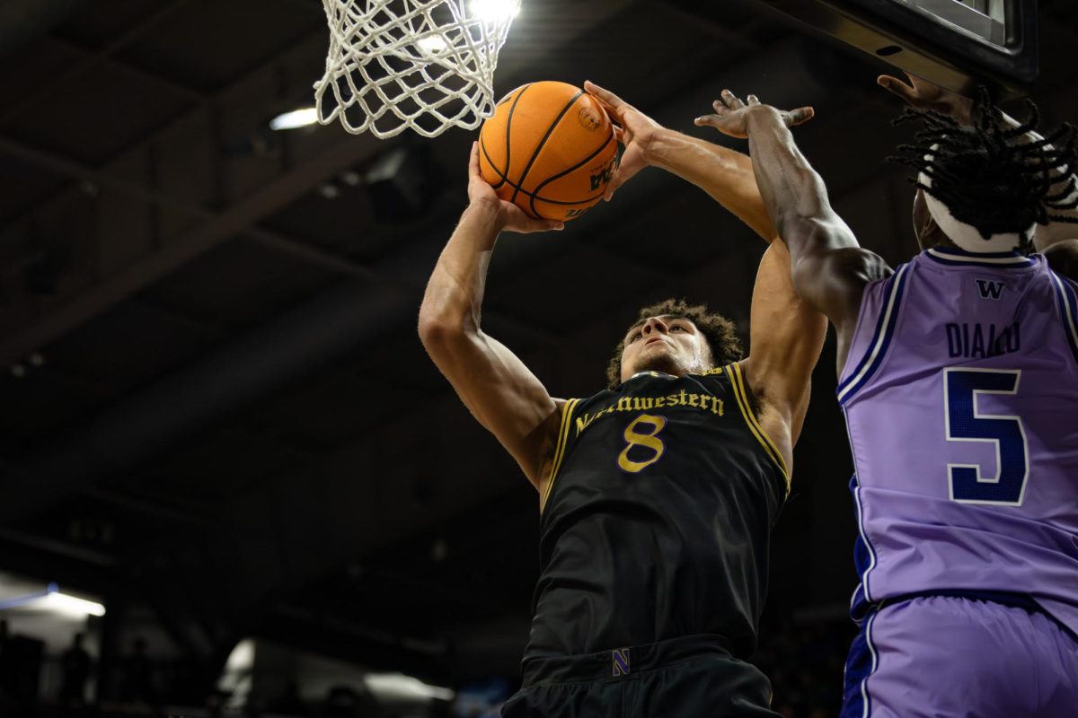A Northwestern player in a black jersey jumps up for a shot against the opponent.