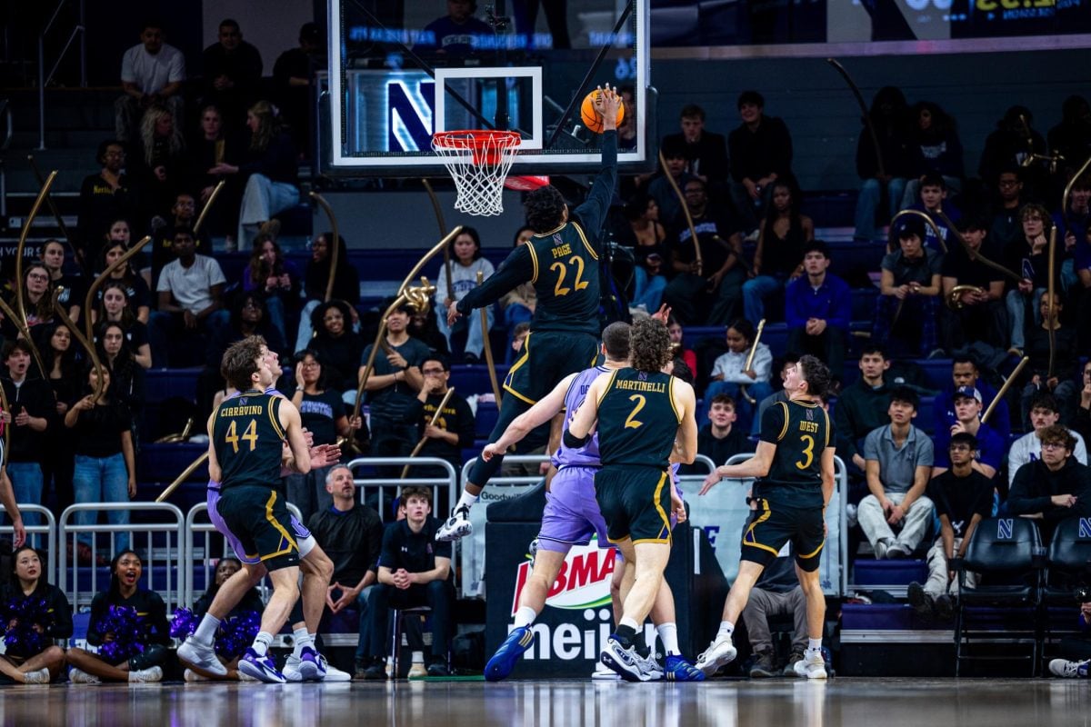 A Northwestern player in a black jersey blocks the ball off the backboard.