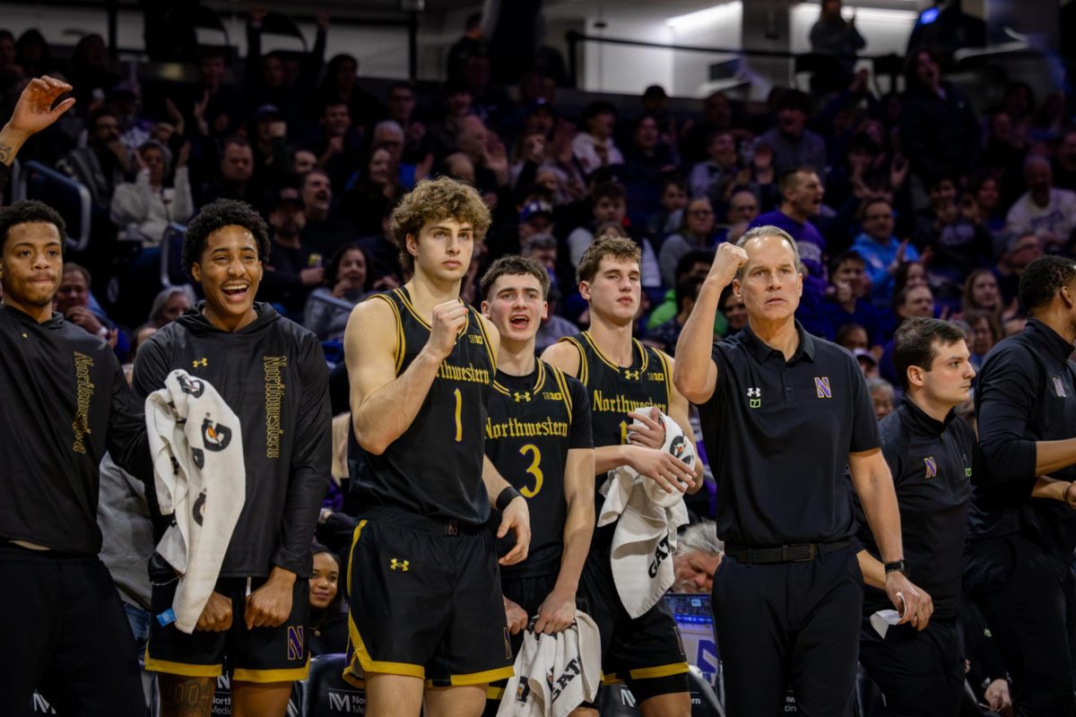 A group of Northwestern players on the bench pump their fists after a basket.