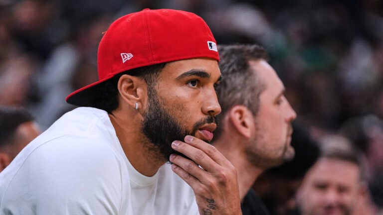 Boston Celtics forward Jayson Tatum, who is recovering from surgery, watches during the first half of a preseason NBA basketball game against the Toronto Raptors, Wednesday, Oct. 15, 2025, in Boston.