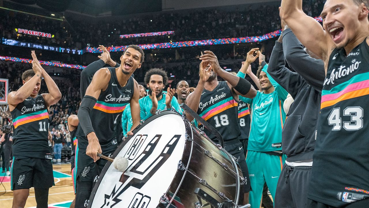 San Antonio Spurs forward Victor Wembanyama (1) hits on a drum as he and teammates celebrate with the Spurs fans after defeating the Oklahoma Thunder in an NBA basketball game in San Antonio, Tuesday, Dec. 23, 2025. (AP Photo/Rodolfo Gonzalez)