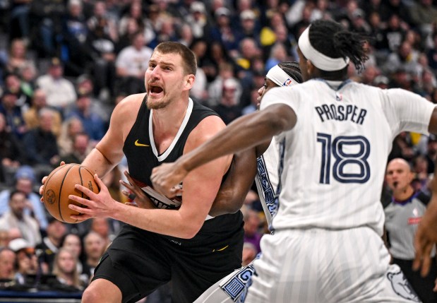 Nikola Jokic (15) of the Denver Nuggets drives on Taylor Hendricks (22) and Olivier-Maxence Prosper (18) of the Memphis Grizzlies during the first quarter at Ball Arena in Denver on Wednesday. (Photo by AAron Ontiveroz/The Denver Post)