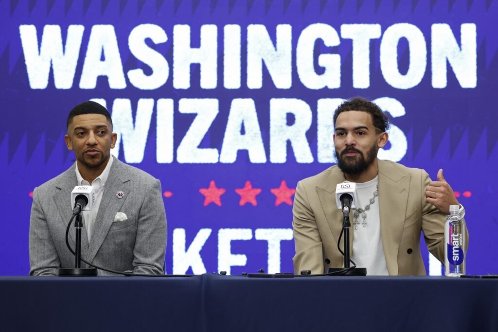 Newly acquired Washington Wizards guard Trae Young (R) speaks at an introductory press conference as Wizards general manager Will Dawkins (L) listens prior to the Wizards' game against the New Orleans Pelicans at Capital One Arena.