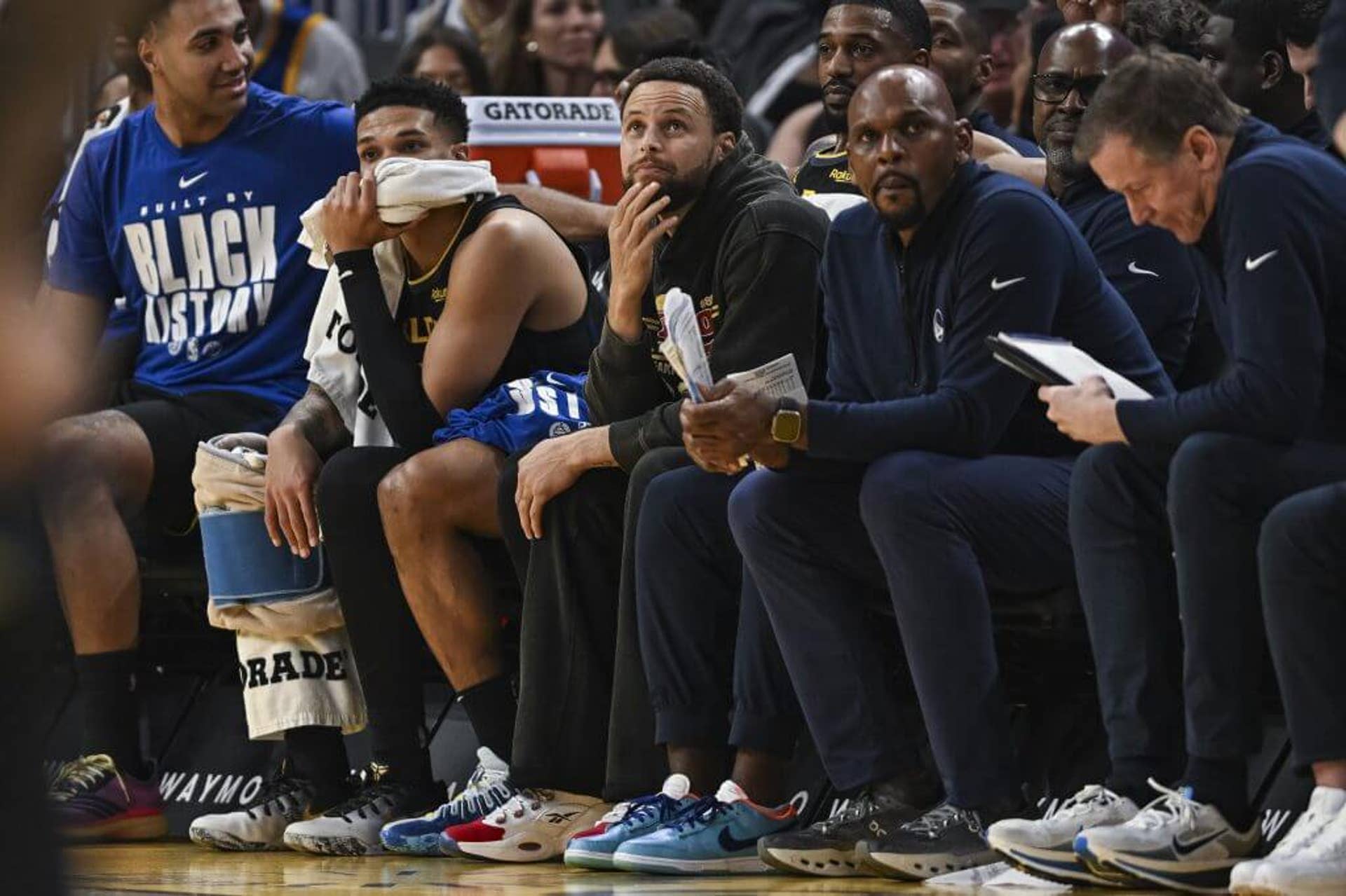 Steph Curry looks on during a Warriors game from the sideline.