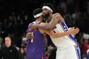 Feb 7, 2026; Phoenix, Arizona, USA; Phoenix Suns guard Devin Booker (1) and Philadelphia 76ers center Joel Embiid (21) embrace after an NBA game at Mortgage Matchup Center. Mandatory Credit: Rick Scuteri-Imagn Images