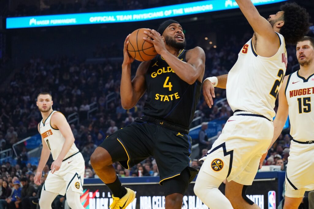 Feb 22, 2026; San Francisco, California, USA; Golden State Warriors guard Moses Moody (4) shoots against Denver Nuggets guard Jamal Murray (27) as guard Christian Braun (0) and center Nikola Jokic (15) look on in the first quarter at Chase Center. Mandatory Credit: David Gonzales-Imagn Images
