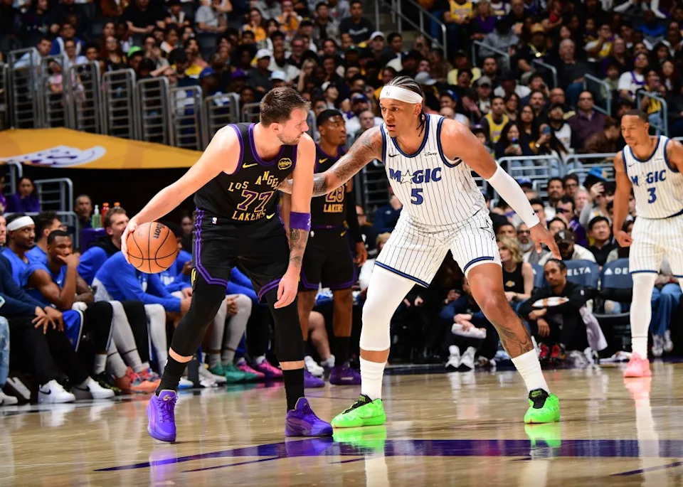 Luka Doncic of the Los Angeles Lakers looks to pass the ball as Paolo Banchero of the Orlando Magic plays defense during the game on February 24, 2026 at Crypto.Com Arena in Los Angeles, California. NBAE via Getty Images