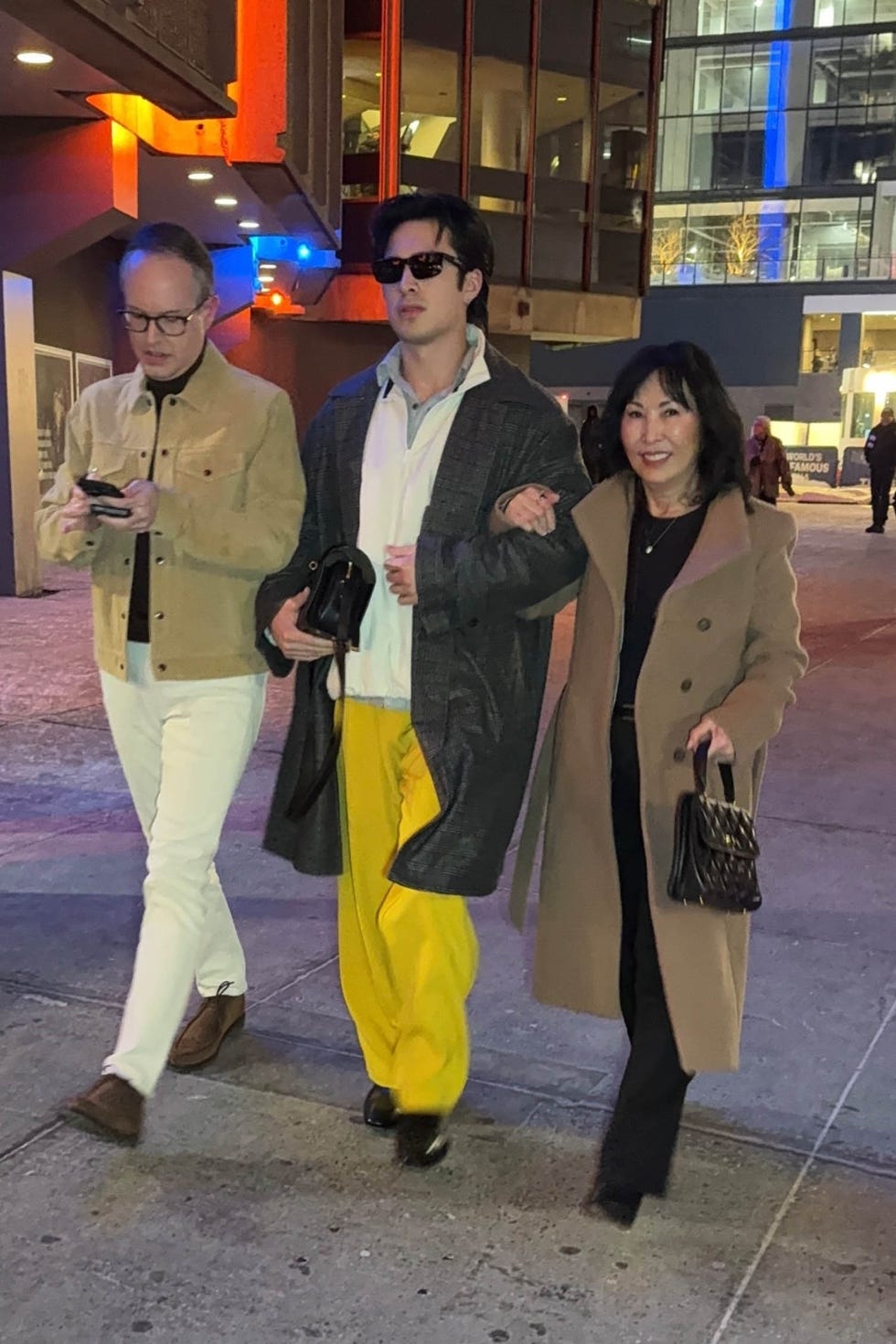group of three people walking in a city setting at night