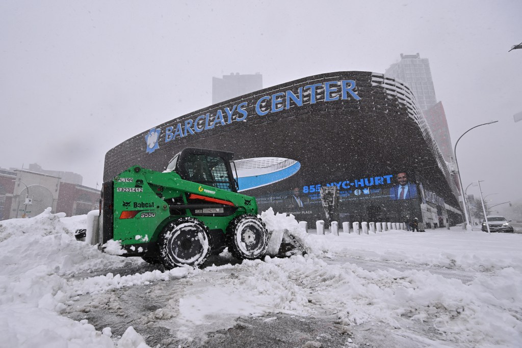 A green Bobcat S550 clears snow outside Barclays Center during a blizzard.