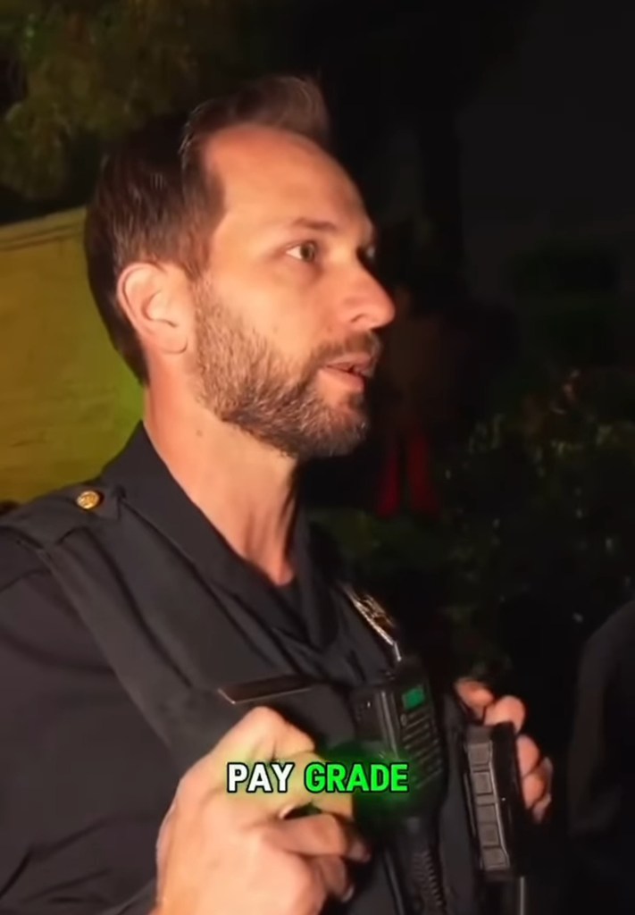 A police officer with a beard and dark uniform talks at night, holding a radio with text overlay "PAY GRADE".